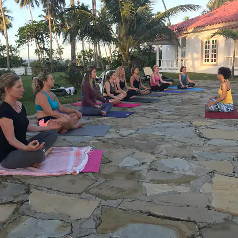 Women meditating on stone terrace mats in front of the villa