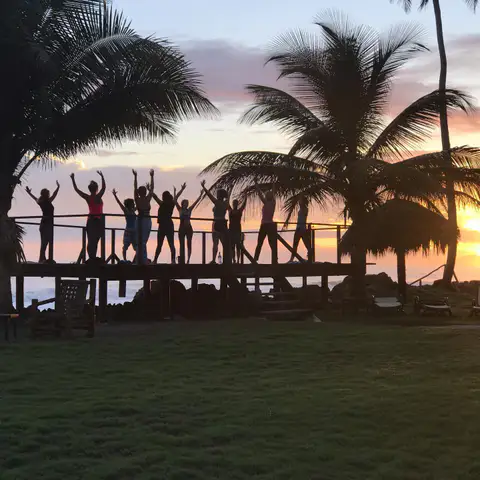 Group raising their arms on the deck at sunset