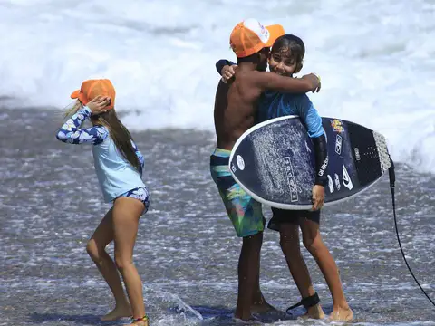 Two children playing with a bodyboard in the shallows