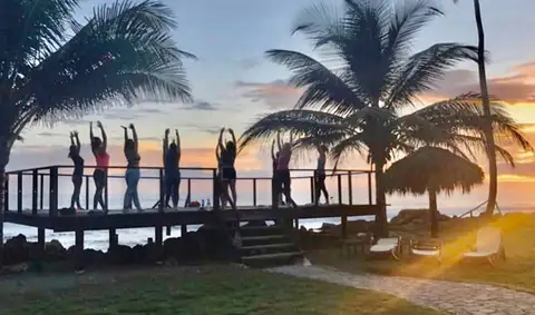 Yoga group silhouetted on the ocean deck at sunset