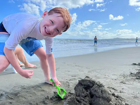 Boy playing with a toy shovel on the beach