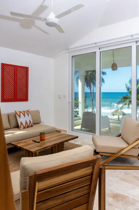 Beachfront suite sitting area with wooden chairs and an ocean view through sliding doors