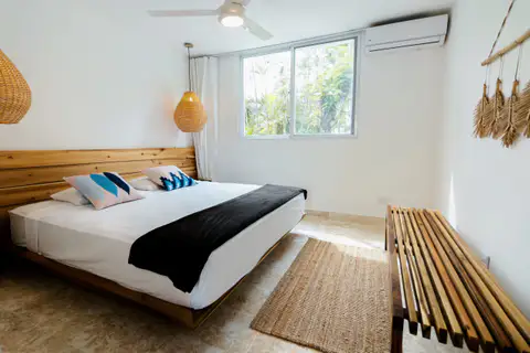 Suite bedroom with a king bed, a wooden bench and a woven wall hanging