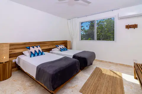 Beachfront suite bedroom with twin beds, a wooden headboard and a garden view window