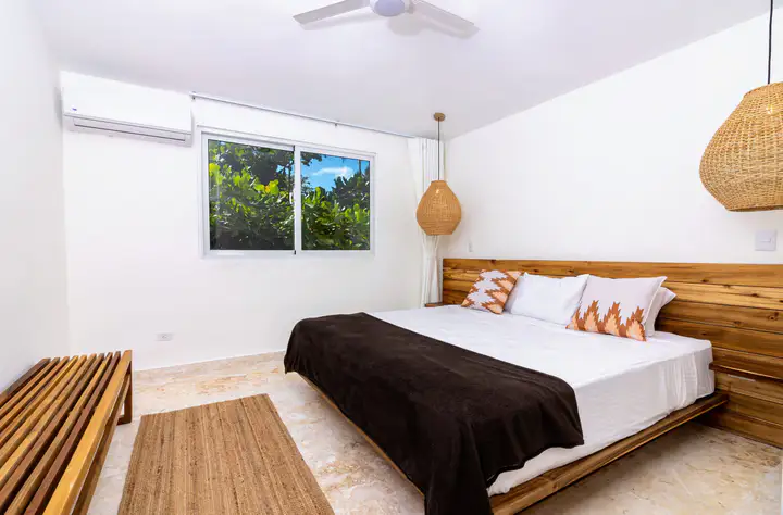 Suite bedroom with a wooden bed and woven pendant lamp