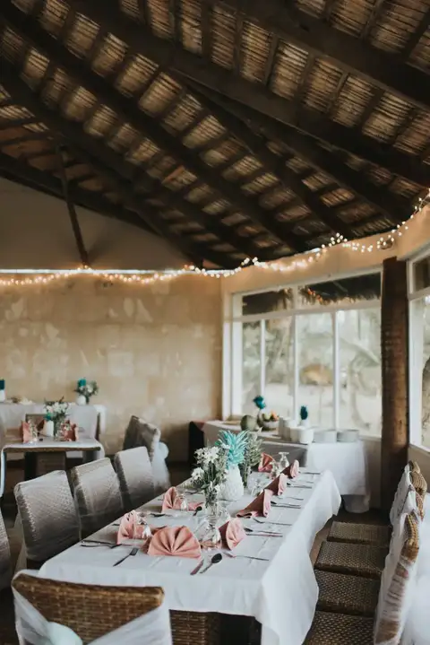Reception tables set under the thatched roof with string lights