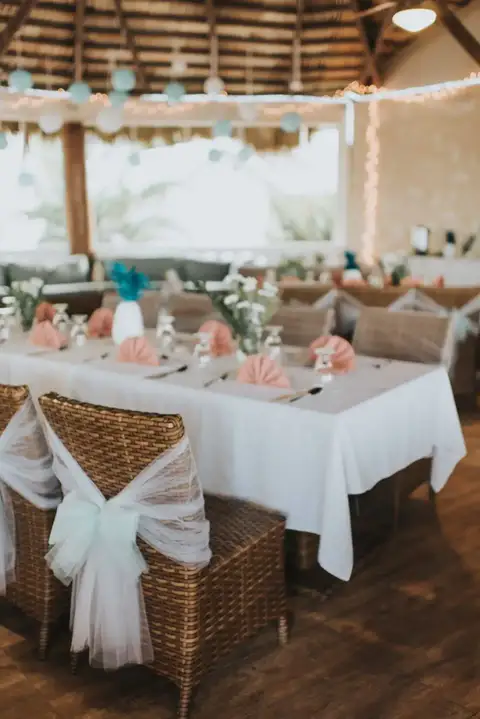 Dining table with white chair covers and pink flowers