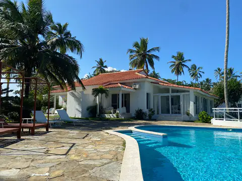 Villa exterior with its pool and red tile roof among palm trees