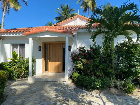 Villa entrance with a wooden door and tropical garden