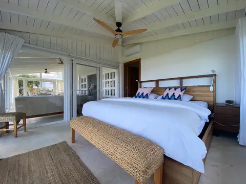 Master bedroom with a white king bed and a woven bench