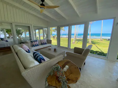 Sunroom lounge with wicker furniture and the sea beyond the lawn