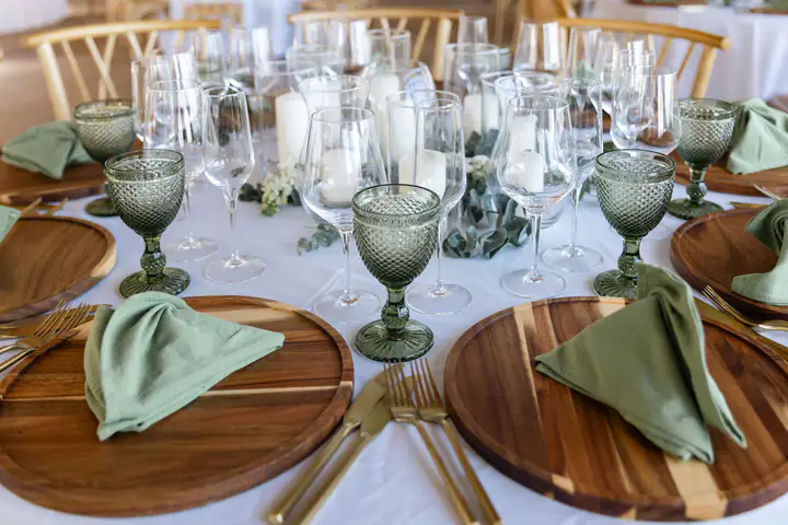Dinner table set with white plates and green glasses