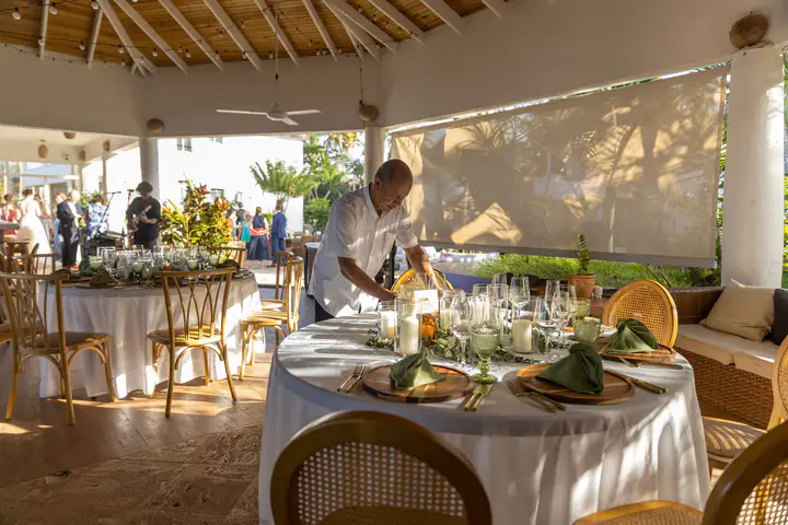 Open air dining table set beneath a thatched roof