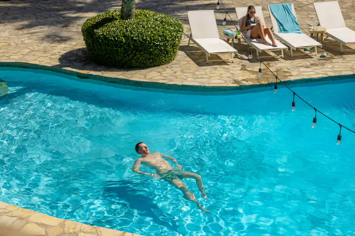 Guest swimming in the pool beside a palm garden