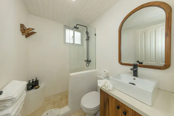 Suite bathroom with an arched mirror and white tiled walls